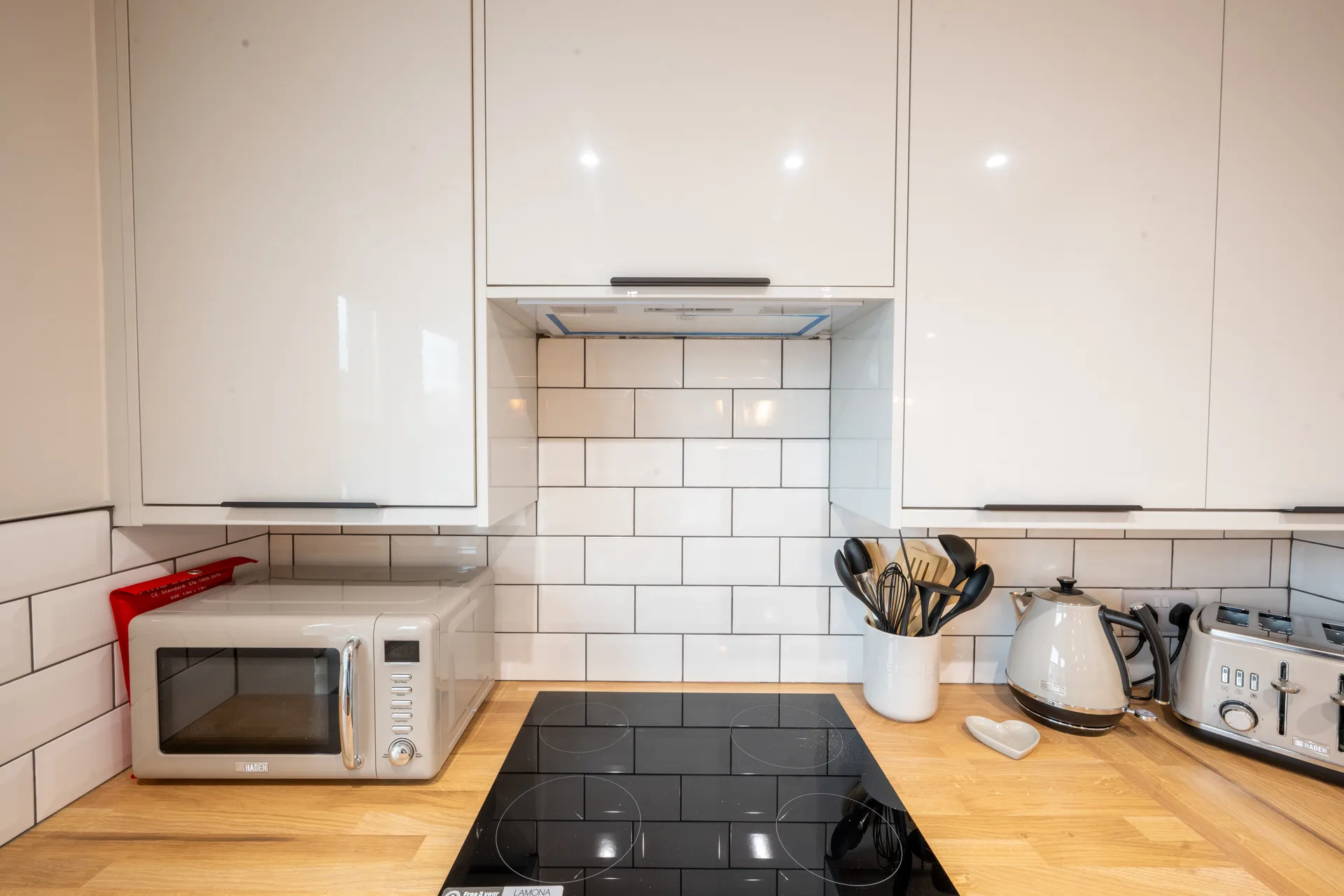 Kitchen hob and countertop beneath white cabinets