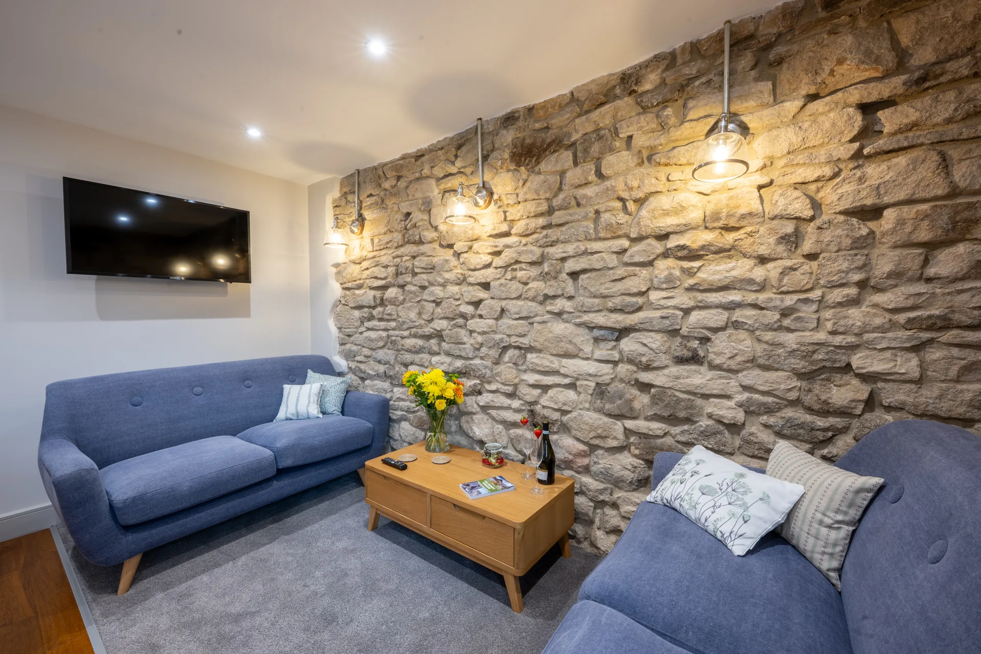 Blue sofa and wall-mounted TV in the stone-walled living room